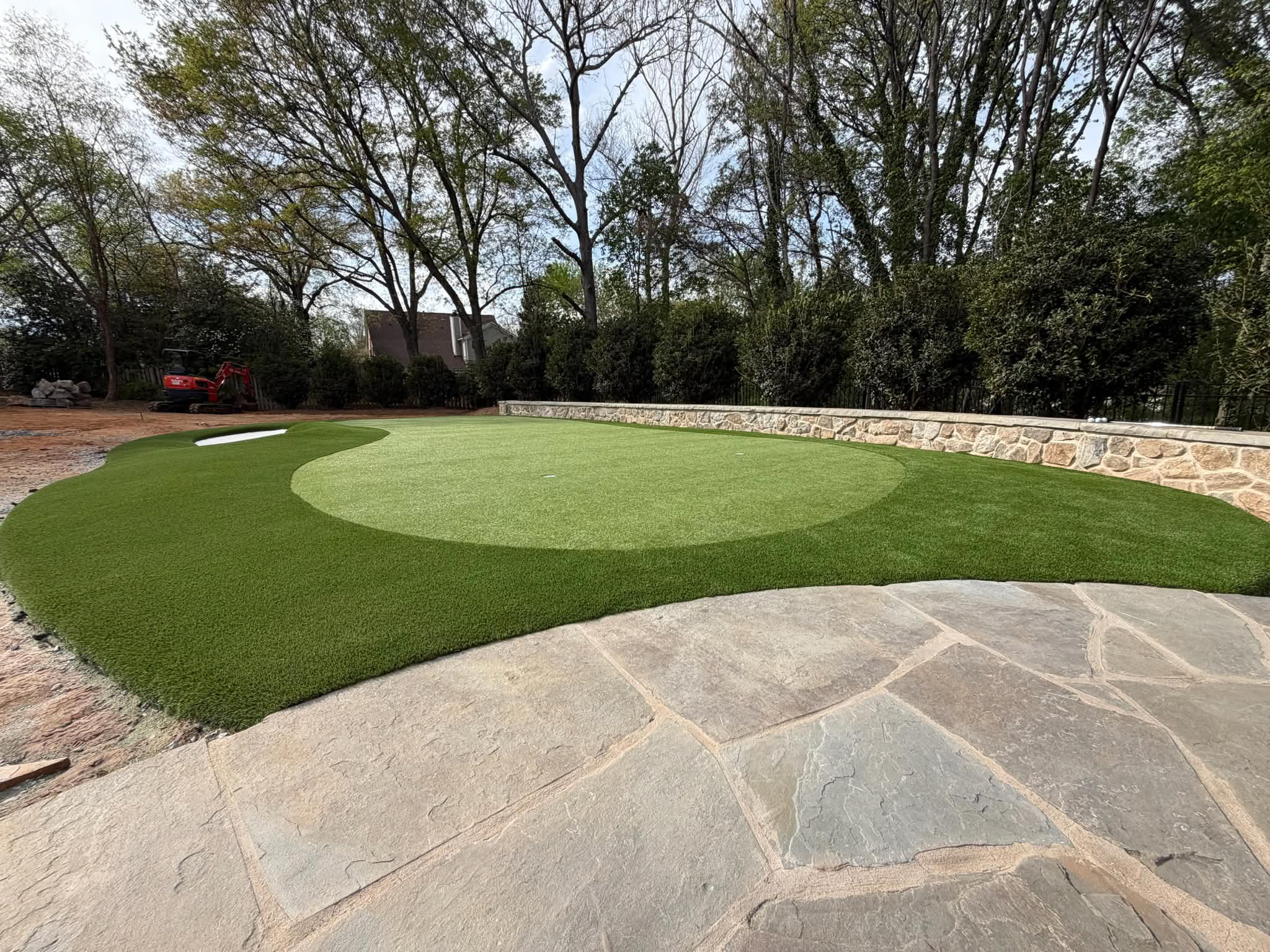 Backyard putting green with clean edging and artificial turf, designed for homeowners near Fort Mill, SC.